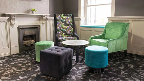 Custom Upholstered High Back Chairs And Custom Upholstered Ottomans With Lila Coffee Table And Compact Laminate Top In The Bar Area At The Kingsford Hotel