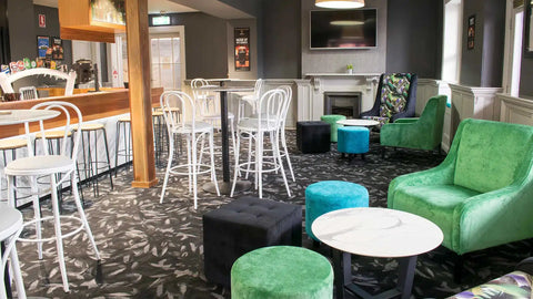 Colman Custom Powdercoated High Back Stools And Custom Upholstered Ottomans With Lila Coffee Table And Compact Laminate Top In Bar Area At The Kingsford Hotel