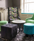 Custom Upholstered High Back Chairs And Custom Upholstered Ottomans With Lila Coffee Table And Compact Laminate Top In The Bar Area At The Kingsford Hotel