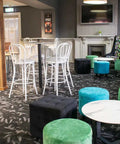 Colman Custom Powdercoated High Back Stools And Custom Upholstered Ottomans With Lila Coffee Table And Compact Laminate Top In Bar Area At The Kingsford Hotel