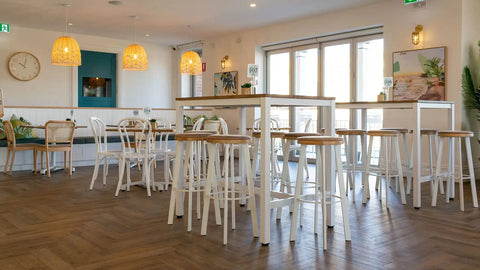 Elm table tops on Henley Bar Table Frames with custom upholstered Nika Bar Stools, no 18 bentwood chairs in white, and Sienna chairs in Natural