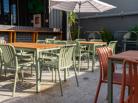 Outdoor dining under umbrellas with timber tables.